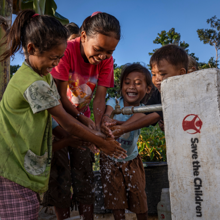 Bambine sorridenti davanti a una fontana aperta.